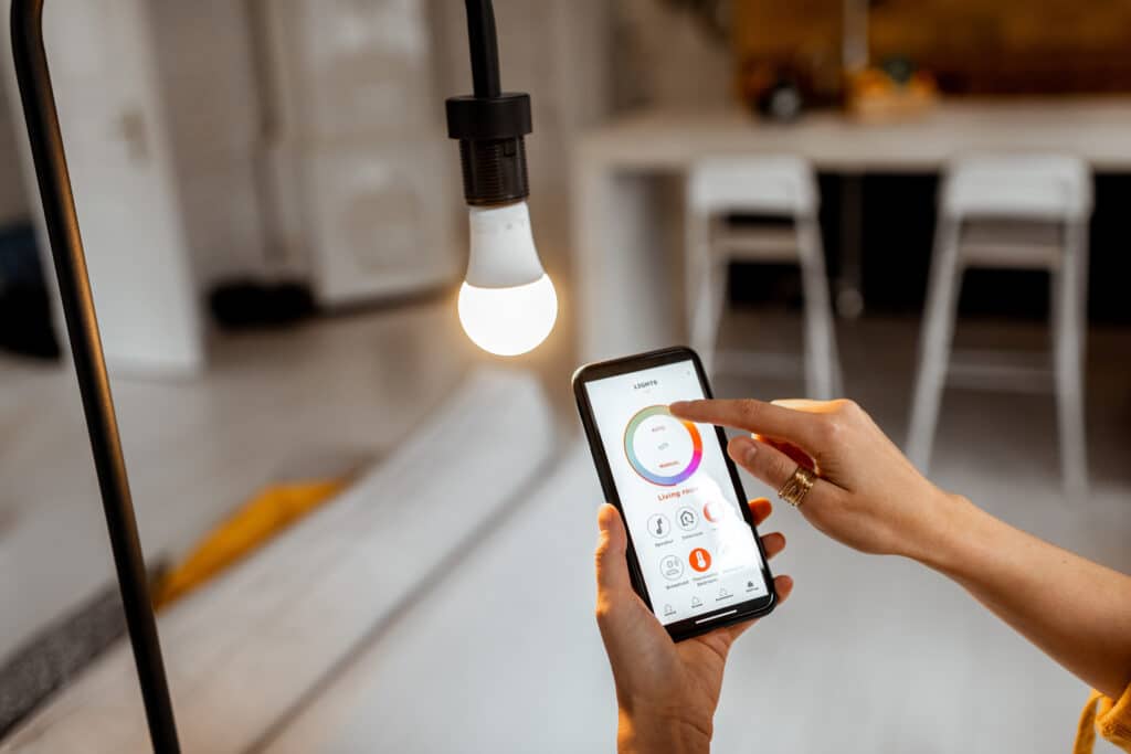 Main d'une personne ajustant la couleur de l'ampoule connectée via l'application "LIGHTS" sur un smartphone.