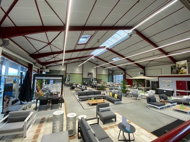Showroom Domino Habitat : mobilier de jardin, salons et parasols dans un vaste espace industriel moderne.